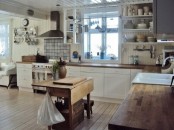 a white farmhouse kitchen with stained butcherblock countertops, stainless steel appliances and a folding stained dining table as a kitchen island