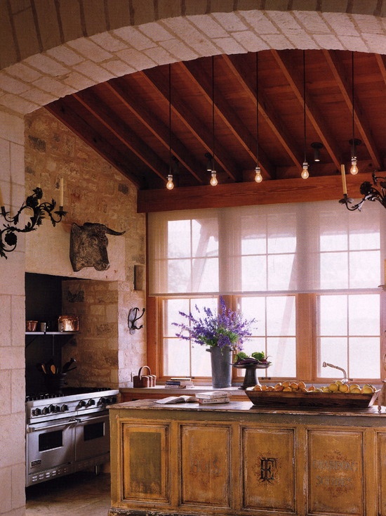 a vintage stained kitchen with an arched ceiling, a large window, stained cabinets and a matching large kitchen island, neutral stone countertops
