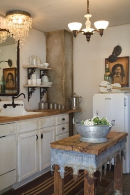 a white farmhouse kitchen with butcherblock countertops, vintage fixtures, a shabby chic wooden kitchen island of a small table