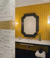 a stylish bathroom with a yellow vertical tile accent wall, a floating sink, a mirror in a catchy frame and marble and yellow tiles on the walls
