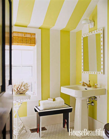 a bold and catchy yellow and white striped bathroom with a free standing sink, a stool and a stand plus a window for natural light