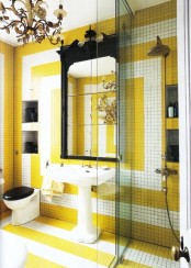 a bold bathroom clad with yellow and white tiles with geometric patterns, a mirror in a window frame, some other black touches for an eye-catchy look